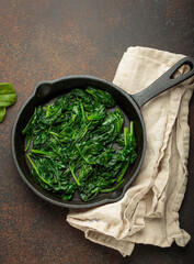 Freshly steamed spinach leaves are served in a cast iron pan, a nutritious and flavorful side dish...