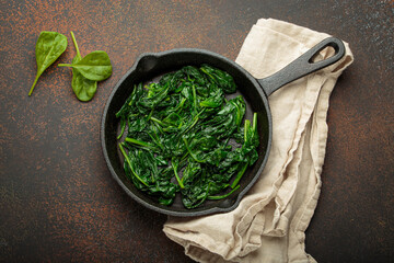 Freshly steamed spinach leaves are served in a cast iron pan, a nutritious and flavorful side dish...