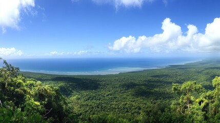 Obraz premium Breathtaking Panoramic View of Lush Green Wilderness Overlooking the Azure Ocean under a Bright Blue Sky with Fluffy White Clouds on a Sunny Day