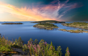 Landscape shot of Lake Ladoga from the top of Rompensari Island. Summer. Stone top of the island, covered with shrubs, flowers and trees. There are many large and small islands in the distance.