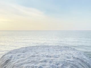 white natural stone pedestal on calm sea background. product display. promotion. mockup. light...