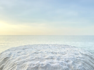 white natural stone pedestal on calm sea background. product display. promotion. mockup. light background. waterline background. seawater surface. minimalistic background