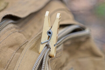 one gray plastic clothespin holds a broken zip on a brown backpack © butus