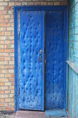 one blue old closed door on brown brick wall of rural house in private yard
