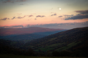 Obraz premium Moon rising over colorful autumn valley at sunset in brecon beacons national park