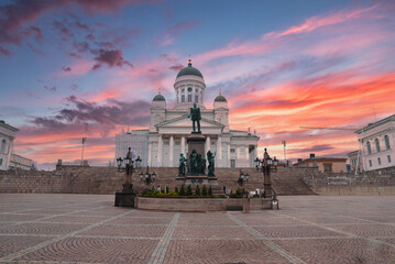 Helsinki Cathedral's neoclassical architecture and green domes stand out against a sunset sky, with...