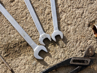 A set of horn wrenches, a screwdriver and metal tongs and pliers on a concrete surface background. The mechanic's working tools. Industrial