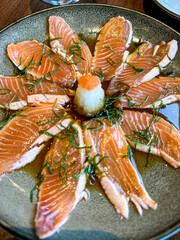 Japanese style salmon carpaccio on a ceramic plate