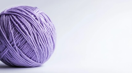 Close up view of a purple ball of yarn against a white background showcasing a knitting and crafting theme