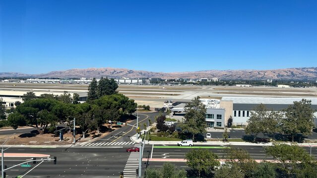 San Jose International Airport with clear blue sky, runways, terminals, and vehicles on roads.