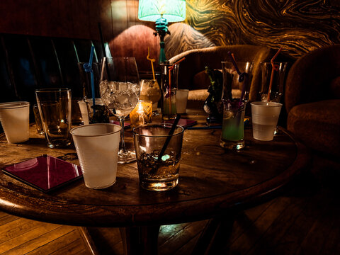 Scattered glasses and empty drinks on a bar table after a party