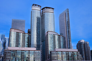 Modern high-rise buildings against a clear blue sky. Primarily with reflective surfaces that mirror the sky and surrounding structures. 