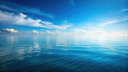 Obraz premium Serene expanse of endless blue, where the azure sky meets the tranquil waters, adorned with wispy white clouds, creating a breathtaking seascape.