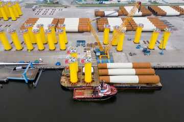 Defzijl, The Netherlands - May 26th 2024 -A tugboat and pontoon for transporting steel monopiles to construct an offshore windpark in the North Sea, The Netherlands