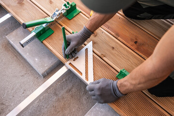 Craftsman Using a Square Tool to Align Wooden Planks on a Deck Renovation Project Outdoors