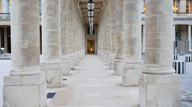 An elegant stone colonnade at Palais Royal in Paris captured with camera movement, highlighting the intricate architecture and historic ambiance. 