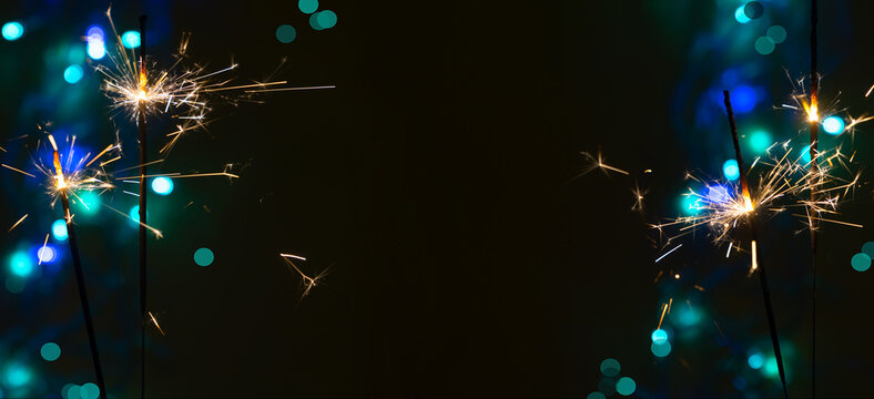 Beautiful glowing sparklers on a dark background. Colorful sparklers sparkling on a black bokeh background create a festive and solemn atmosphere. Christmas festive background