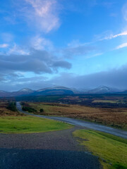 Snow-capped mountains and rolling hills under a cloudy so 
