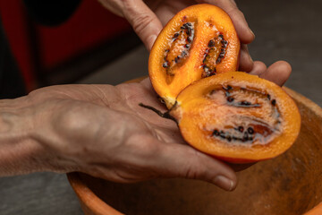 A tree tomato cut in half on the palm of a woman's hand