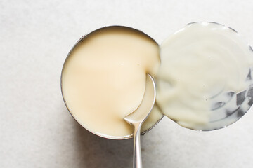 Overhead view of an opened tin of condensed milk with the lid, top view of canned condensed milk