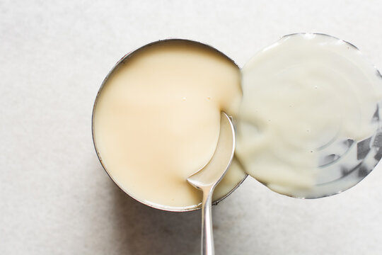 Overhead view of an opened tin of condensed milk with the lid, top view of canned condensed milk