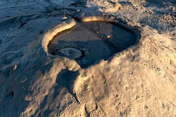 Close-up of a bubbling mud pool in a volcanic area, capturing the texture and fluid motion of the...