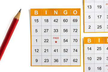 yellow and white paper bingo cards with a pencil on white background.
