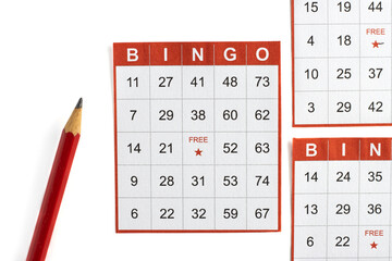 red and white paper bingo cards with a pencil on white background.