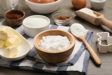 Fototapeta premium Baking powder in bowl and other products on wooden table, closeup