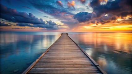 Fototapeta premium A wooden pier extends into a tranquil sea, the horizon ablaze with the vibrant hues of a breathtaking sunset.