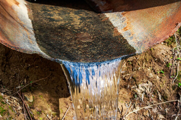 Clear water flows through a large diameter iron pipe