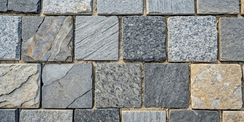Obraz premium A close up texture of a paved path consisting of various sizes of gray and tan stone tiles.