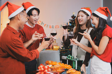 Group of young Asian man and women as friends having fun at a New Year's celebration, holding gift...