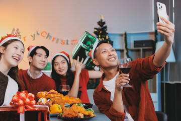 Group of young Asian man and women as friends having fun at a New Year's celebration, holding gift...