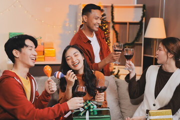 Group of young Asian man and women as friends having fun at a New Year's celebration, holding gift...