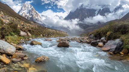 panoramic view of a rocky river with fast-flowing crystal clear water, winding through a rugged landscape. The towering mountains in the background are framed by clouds