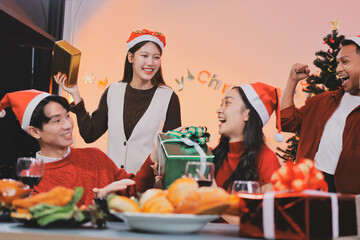 Group of young Asian man and women as friends having fun at a New Year's celebration, holding gift...