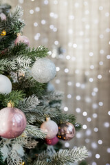 Christmas tree decorated with toys in silver and pink color. ribbons and lights glowing garland....
