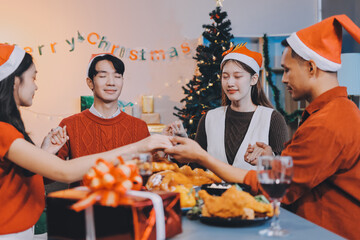 Group of young Asian man and women as friends having fun at a New Year's celebration, holding gift...