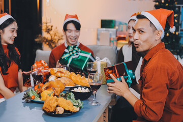 Group of young Asian man and women as friends having fun at a New Year's celebration, holding gift...