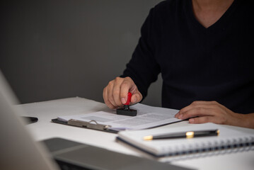 Man stamping approval of work finance banking or investment marketing documents on desk.