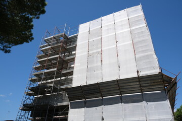 Building maintenance. Renovation work on a building.Scaffolding for construction work mounted on the facade of a condominium. Blue sky background. Italy