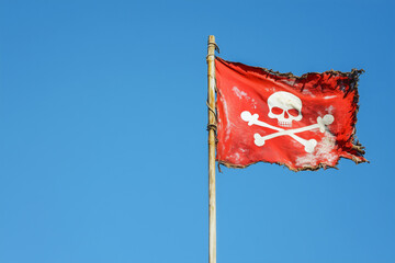 Red pirate flag jolly roger on sky background, copyspace