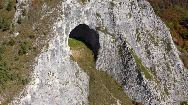 Aerial view of big cave entrance in vertical mountain wall