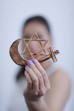 Religious symbols in hand. Jewish Star of David, Muslim star and Crescent, Christian Cross. Religion, interreligious and interfaith dialogue concept.
