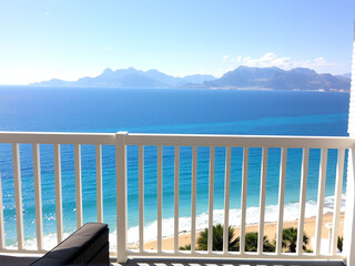 Fototapeta premium A serene balcony view showcasing the ocean and majestic mountains in the background.