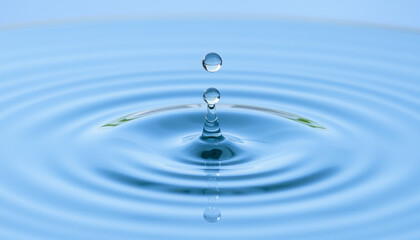 Crystal-clear raindrop bursts into a vibrant blue splash, leaving a mesmerizing ripple on the water's surface