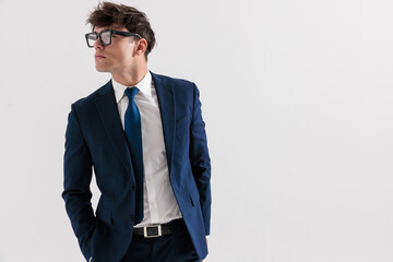 attractive man in his 20s in navy blue suit holding hands in pockets