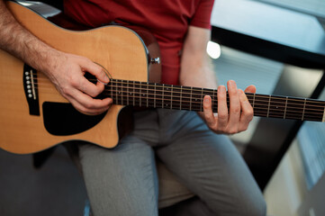 Guitarist on acoustic guitar playing melody in studio. Close up musician instrument