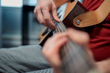 Guitarist on acoustic guitar playing melody in studio. Close up musician instrument